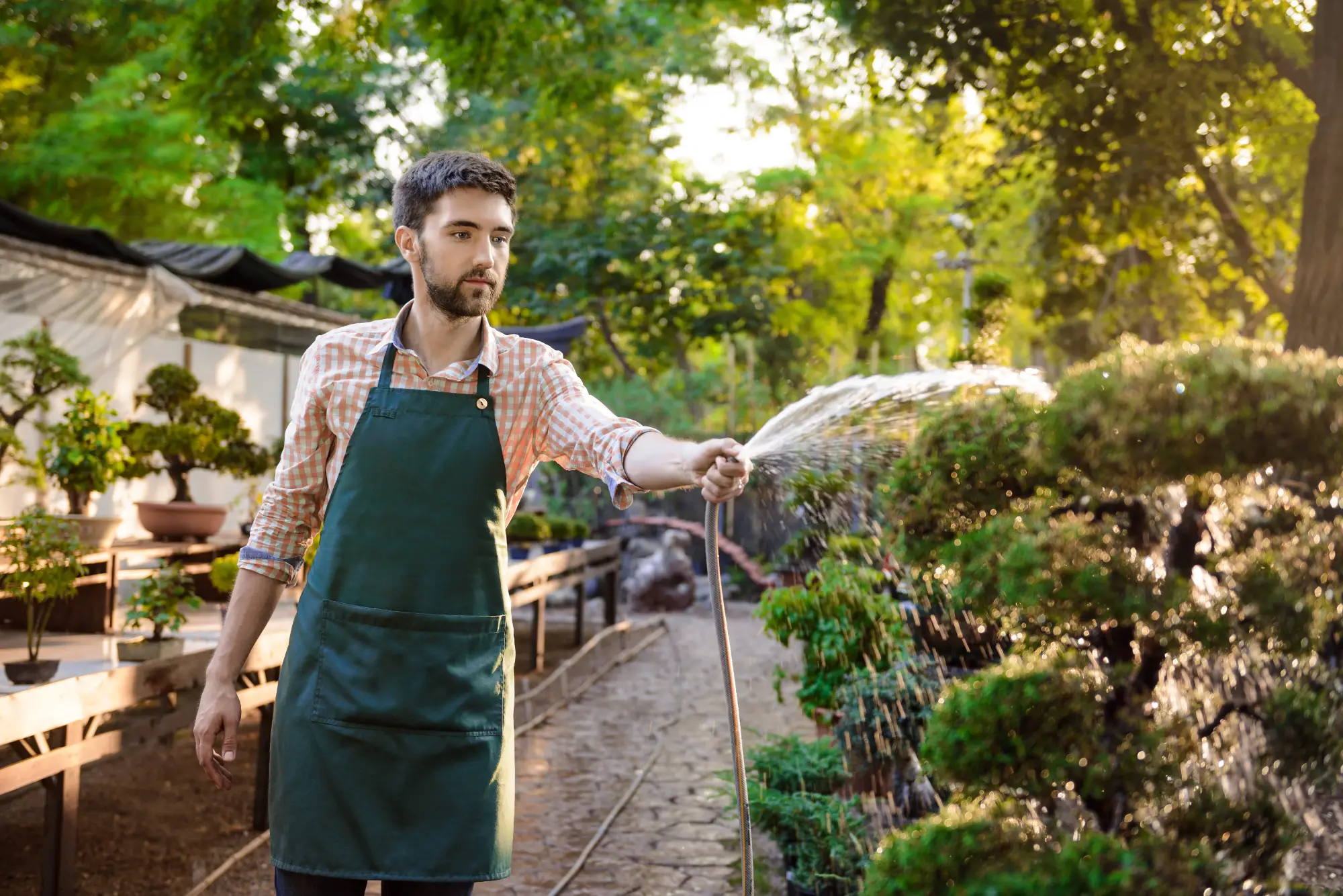 Giardiniere sorridente che si prende cura delle piante con sistema di irrigazione